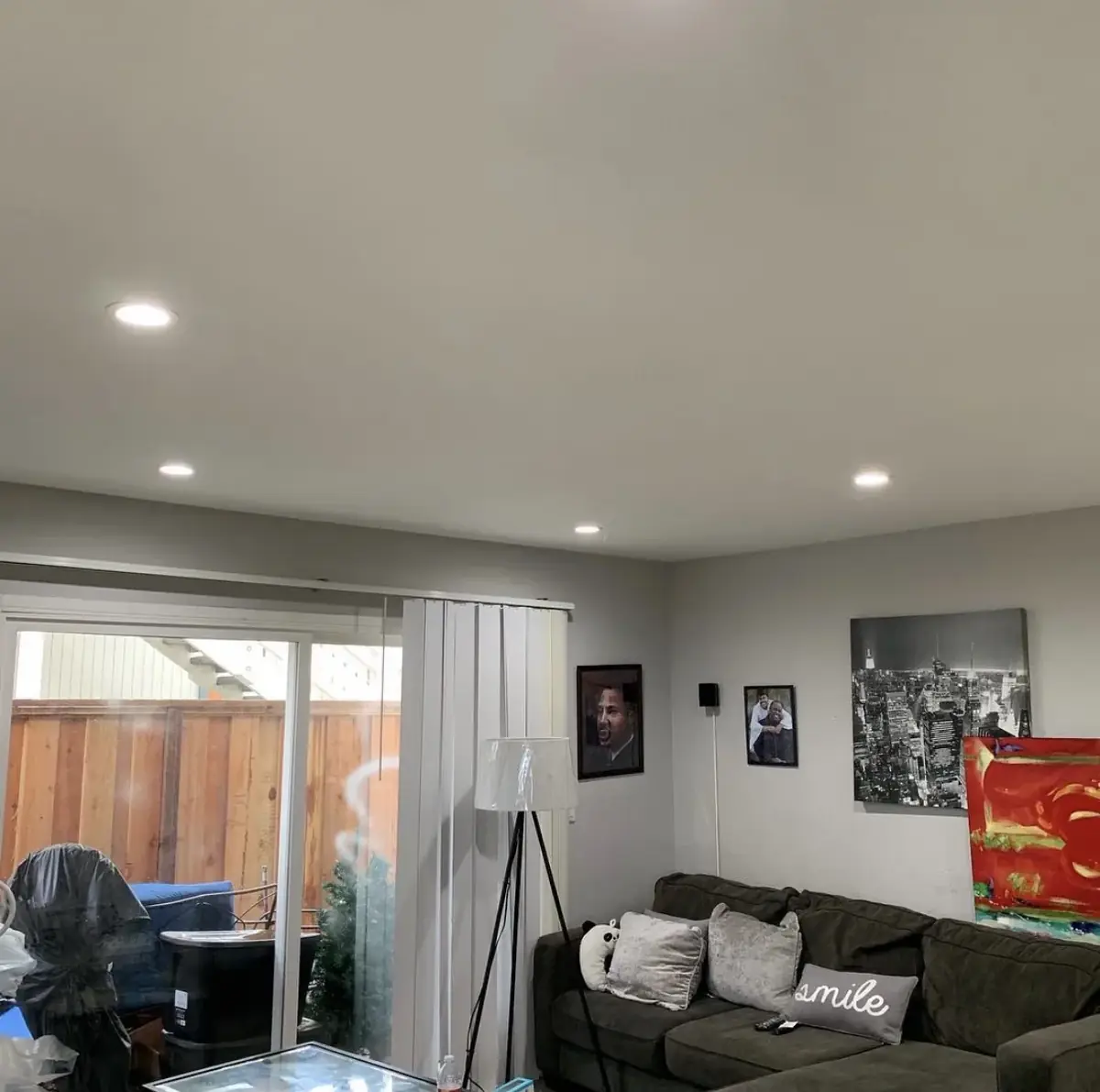 Living room with recessed lights in the ceiling, a sliding door to a fenced backyard, a sectional sofa and framed pictures on the wall