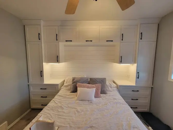 Bedroom with white built-in wardrobes and under-cabinet LED strip lighting over a shiplap headboard wall, ceiling fan above